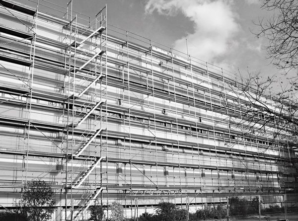 Durch das Anbringen einer Podesttreppe an einem Fassadengerüst können Handwerker deutlich schneller und sicherer im Gerüst auf- und absteigen als mit einem integrierten Leiternaufstieg und dabei mühelos Arbeitsmaterial und Werkzeug mitnehmen. geruest.com